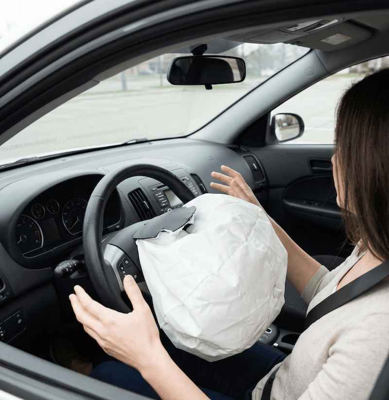 Driver's hands react to unexpected accidental airbag deployment in an undamaged car, illustrating an auto defect. Face turned away, not visible.